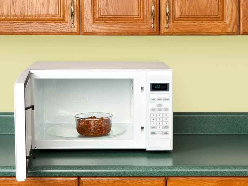 A man is adding wine into the mixture of caramelized onions, garlic tomato paste.