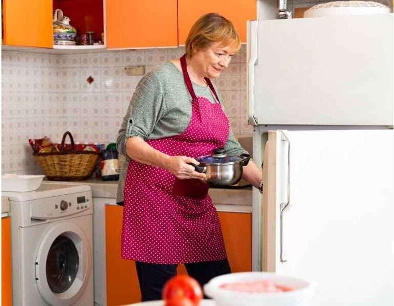 A lady putting her cheesecake in the fridge to let it rest