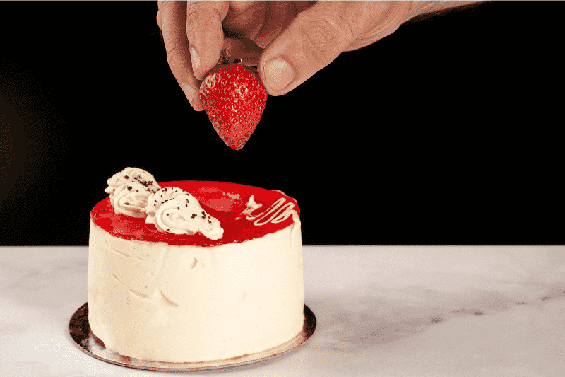 Putting a strawberry topping on the cheesecake